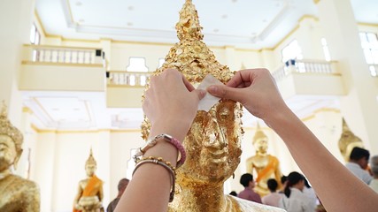 Buddhists attach gold leaf to the Buddha image. To worship the Lord Buddha