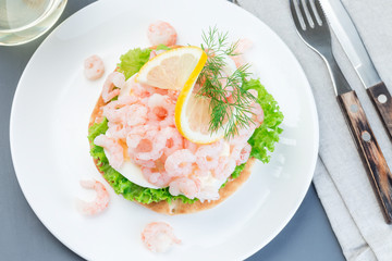 Traditional savory swedish sandwich with soft white bread vetekaka, lettuce, eggs, mayonnaise, shrimps, dill and lemon, horizontal, top view