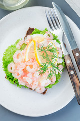 Traditional savory swedish sandwich with a dark bread, lettuce, eggs, mayonnaise, shrimps, dill and lemon, vertical, top view