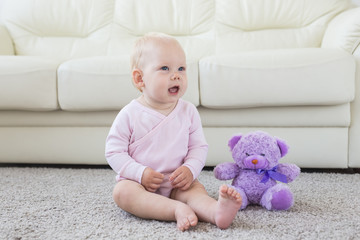 Cute little baby girl wearing pink clothes sitting on carpet