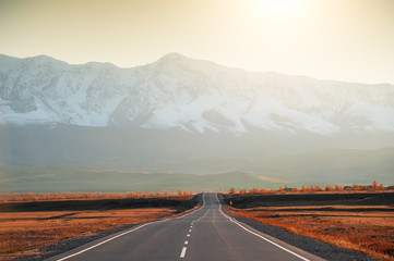 Autumn road in the mountains at sunset. Chuysky tract in Altai Republic, Siberia, Russia. View of North-Chuya mountain ridge