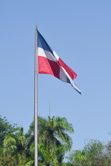 Flag of Dominican Republic (DR) waving in the wind with blue sky on background