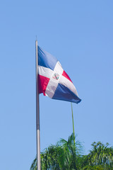 Flag of Dominican Republic (DR) waving in the wind with blue sky on background