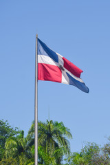 Flag of Dominican Republic (DR) waving in the wind with blue sky on background