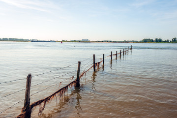 Naklejka premium Fence with barbed wire into the river