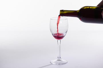 Red wine bottle pour glass on white background with copy space