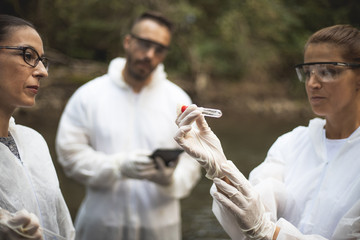 Scientist in protective suits takeing water samples from the river