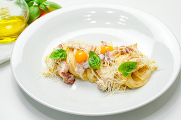 Spaghetti Carbonara with bacon, quail egg, Basil and Parmesan. Spaghetti on white wooden background.