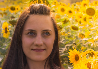 Naklejka premium young woman portrait in a sunflower field