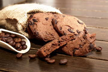 Stacked chocolate chip cookies on brown wood background. Concept for a tasty snack. Sweet dessert.  Selective focus. Close up.Coffee beans.