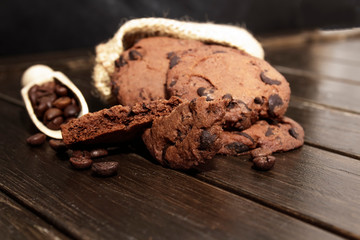 Stacked chocolate chip cookies on brown wood background. Concept for a tasty snack. Sweet dessert.  Selective focus. Close up. Coffee seeds.