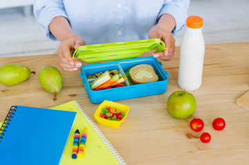 Closeup of female hands packing lunch box on a table