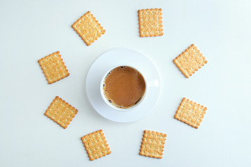 Obraz na płótnie Canvas White cup and saucer with coffee foam and cracker cookies. On a white background. View from above.