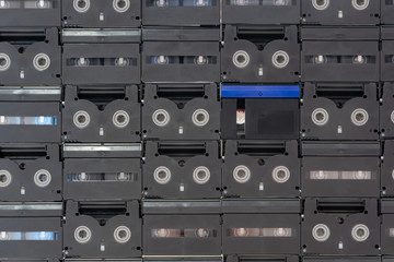 Set of old audio cassette tape on the wall background, large collection of analog black magnetic record technology