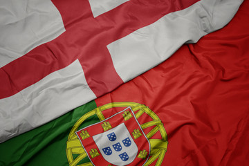 waving colorful flag of portugal and national flag of england.