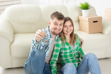 Obraz premium Young married couple with boxes and holding flat keys.