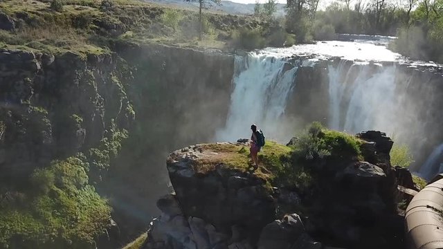Cinematic Slow Motion Aerial of Female Hiker on Cliff in Front of White River Falls, Oregon, USA