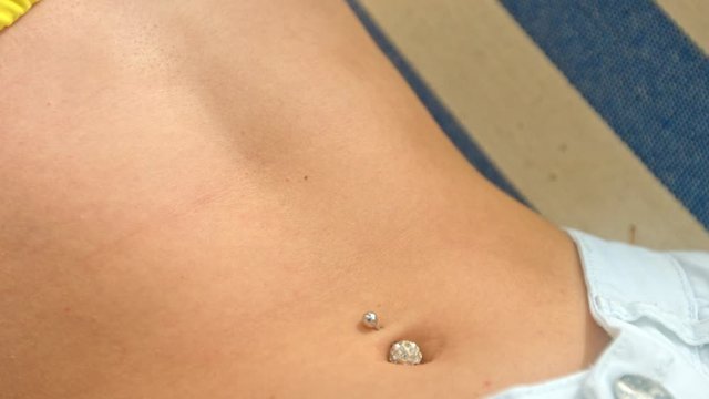 Close up shot of a young woman's stomach, as she rocks back and forth in a hammock