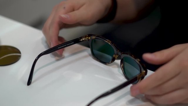 Closeup of optician checking sunglasses on a table top to make sure they are level.