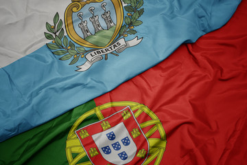 waving colorful flag of portugal and national flag of san marino.