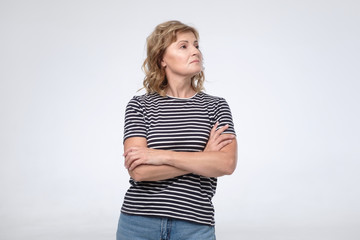 Caucasian arrogant mature woman wth folded hands looking aside.