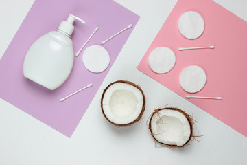 Natural cosmetics, skin care products. Coconut, bottle of cream, cosmetic accessories on colored background. Top view. Flat lay style