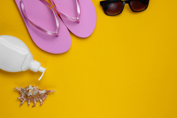 Summer still life. Beach accessories. Fashionable beach pink flip flops, sunblock bottle,...