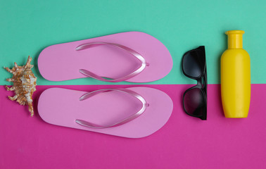 Summer still life. Beach accessories. Fashionable beach pink flip flops, sunblock bottle,...