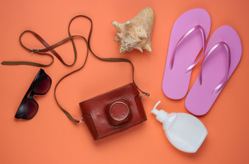 Summer still life. Beach accessories. Fashionable pink flip flops, retro camera, sunblock bottle,...