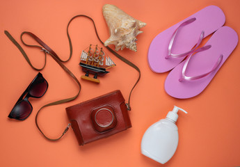 Summer still life. Beach accessories. Fashionable pink flip flops, retro camera, sunblock bottle,...
