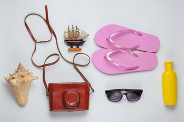 Summer still life. Beach accessories. Fashionable pink flip flops, retro camera, sunblock bottle,...