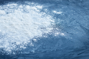 Side view of sprinkled baking wheat flour with shallow depth of field on abstract blue textured background