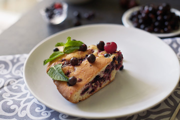 Piece of pie with blueberries, rasberry and mint for dessert on a white plate, napkin. Pieces of delicious homemade cake