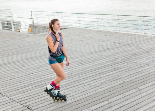 Young Attractive Sport Woman Roller Skating On The Beach