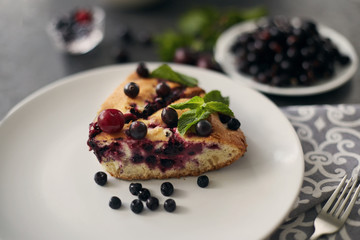 Piece of pie with blueberries, rasberry and mint for dessert on a white plate, napkin. Pieces of delicious homemade cake