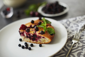 Piece of pie with blueberries, rasberry and mint for dessert on a white plate, napkin. Pieces of delicious homemade cake
