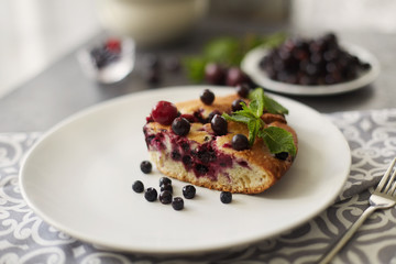 Piece of pie with blueberries, rasberry and mint for dessert on a white plate, napkin. Pieces of delicious homemade cake