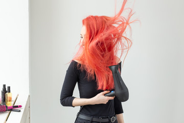 Hairdresser, beauty salon and people concept - young woman hair stylist with hair dryer on white...