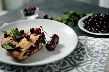 Piece of pie with blueberries, rasberry,cherries and mint for dessert on a white plate, napkin. Pieces of delicious homemade cake