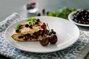 Piece of pie with blueberries, rasberry and mint for dessert on a white plate, napkin. Pieces of delicious homemade cake on a background