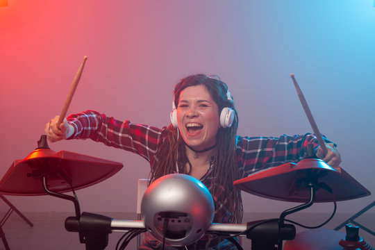Electronic drum set, music and hobby concept - young woman drummer playing in headphones