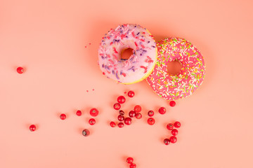 Round pink donuts on pink background with red cranberry berries.