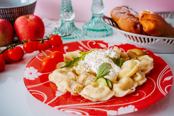 Dumpling on a plate with tomatoes and spinach leaves.