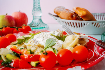 Dumpling on a plate with tomatoes and spinach leaves.