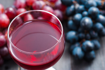 glass of red wine and grapes on black wooden table background