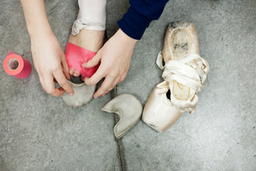 woman putting on ballet shoes
