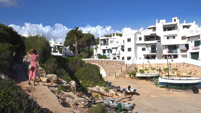 Tourist woman taking a selfie in the traditional fishing village of Binibeca on the mediterranean coast of Menorca, Spain. Town with Ibiza style.