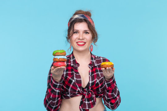 Positive young pin-up girl model holding in hands four multicolored donuts posing on a blue background. Cooking concept for desserts and sweets.