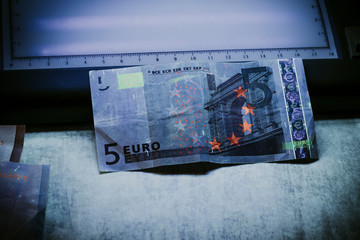 5 euro authentication. ultraviolet light shines on them.