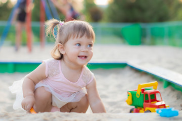 little baby girl playing in the sandbox in kindergarten